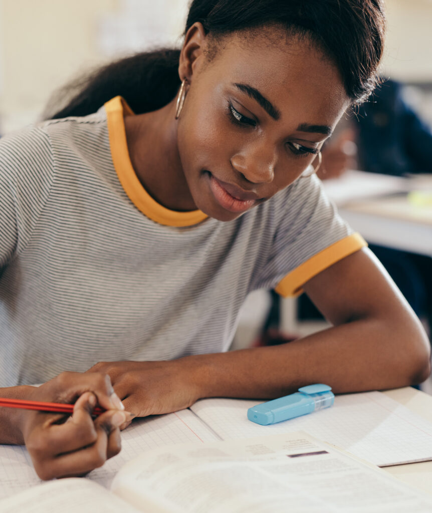 woman holding a pencil leaning over desk filled with papers and a highlighter