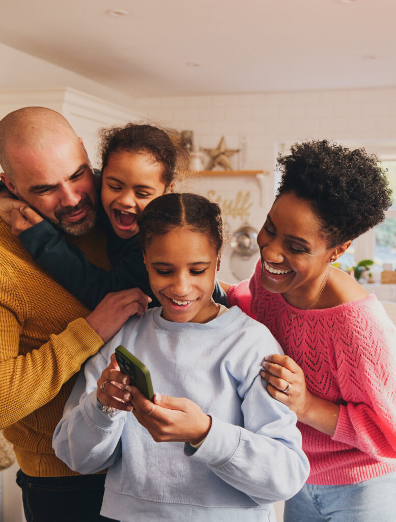 family smiling, looking at the oldest daughter's phone