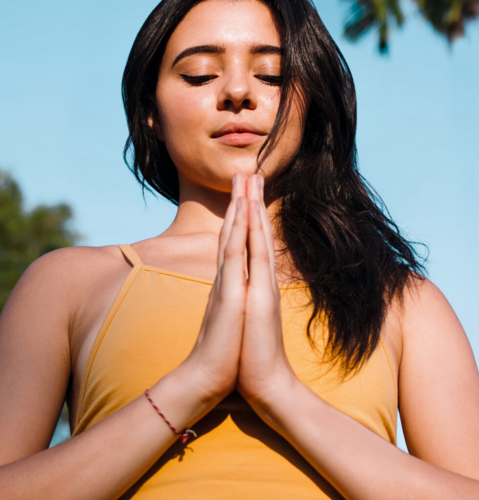 Young woman looking down calm with the palms of her hands together