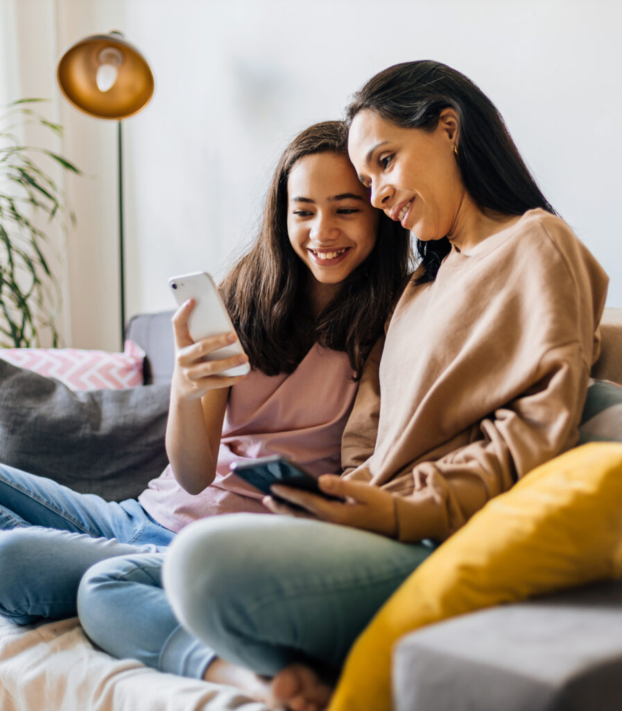 Daughter showing her mom something on her phone while they sit on a couch