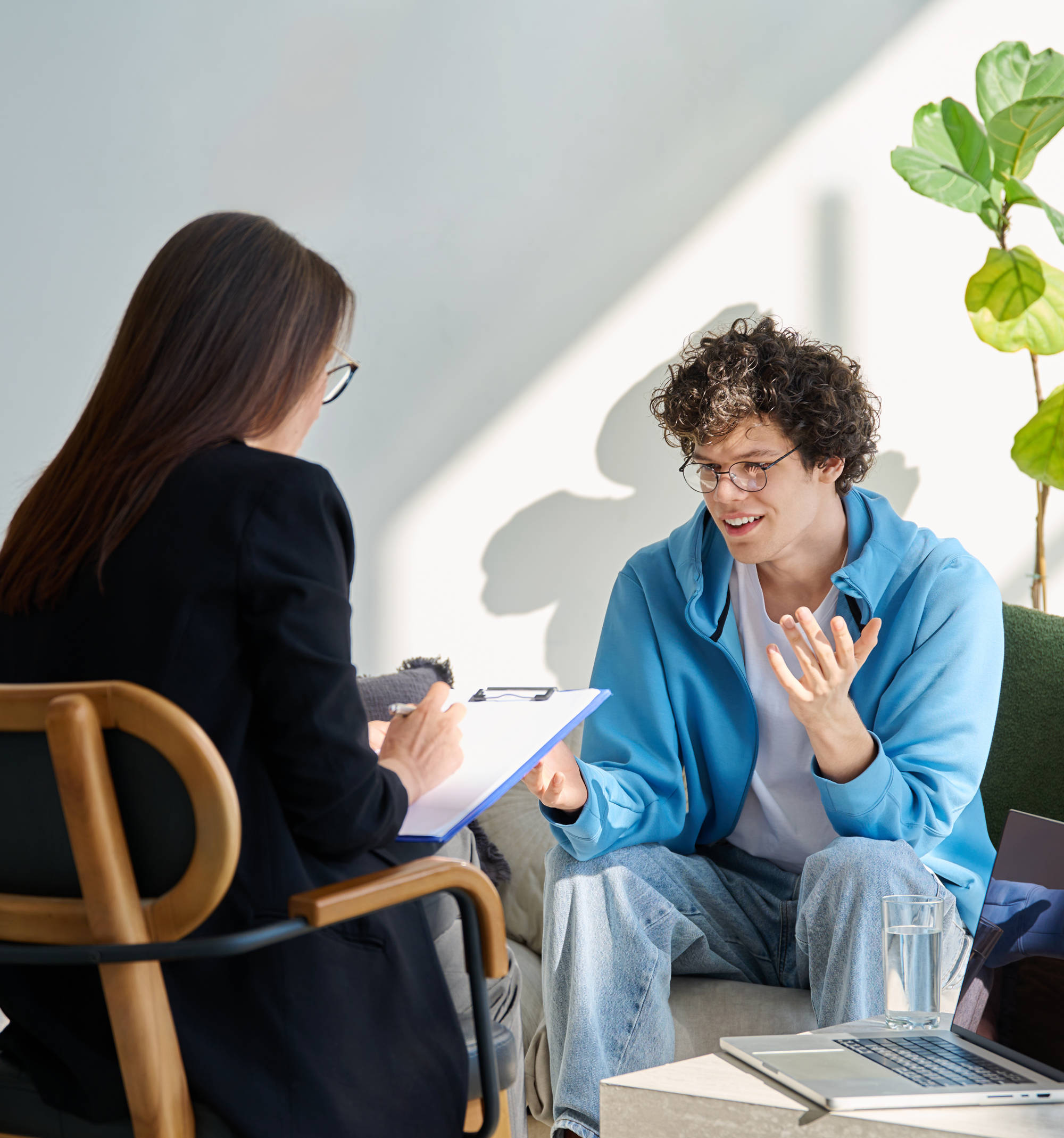 Man sitting facing and talking to a counselor who is taking notes