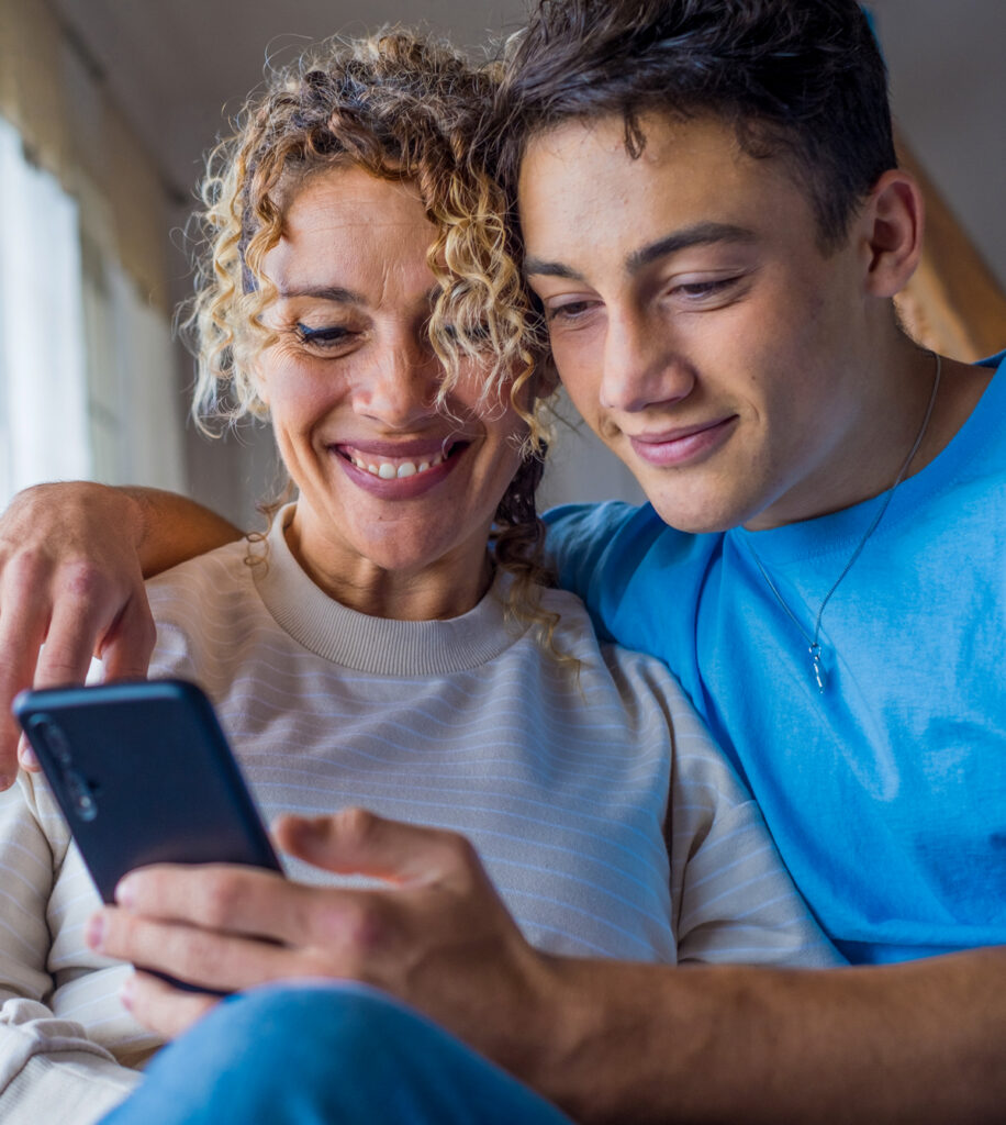 son showing his mom something on his phone with his arm around her
